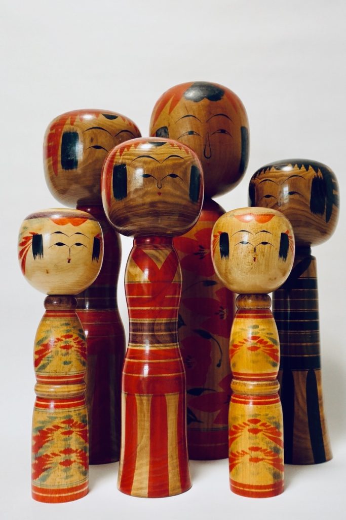 Traditional Japanese kokeshi dolls, handcrafted from wood and decorated with colorful patterns, originating from Japan's Tohoku region.